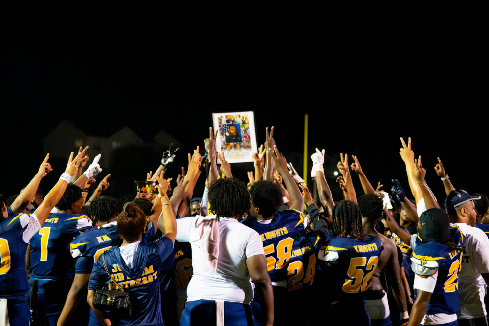 Ballou football players honor Terry Bennett during halftime, raising two fingers in remembrance of No. 2.